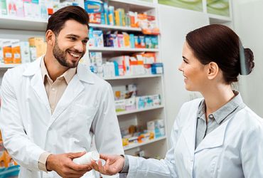 Pharmacist handing prescription bottle to another pharmacist