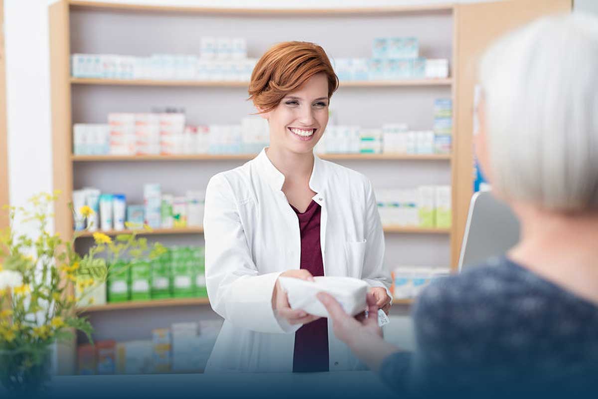 CFOCashFlow1 Smiling pharmacist handing prescription to patient over the counter